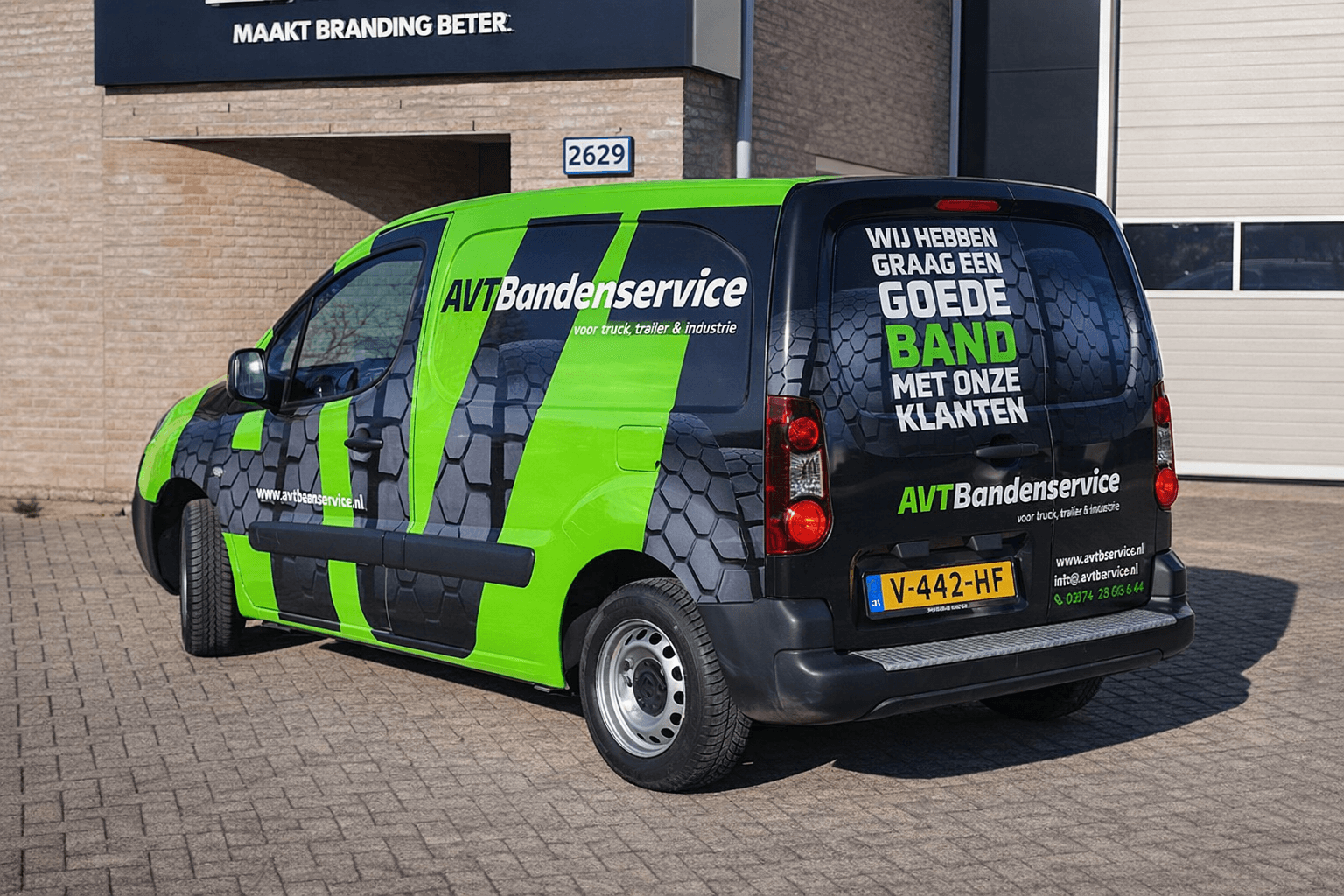 Groen-zwarte bestelwagen met opvallende voertuigbelettering van AVT Bandenservice, voorzien van grote witte tekst, felgroene banen en een bandenprofiel-graphic op de zijkant en achterdeuren, geparkeerd voor een bedrijfspand.