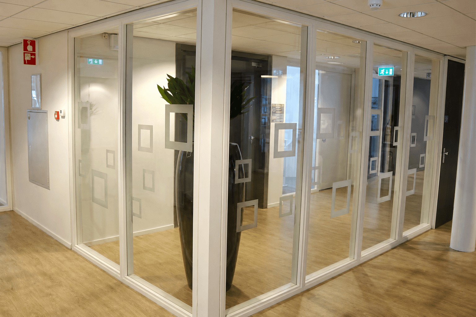 Glazen kantoorwanden met matte vierkante raamfolie als decoratieve privacyfolie in een moderne gang.