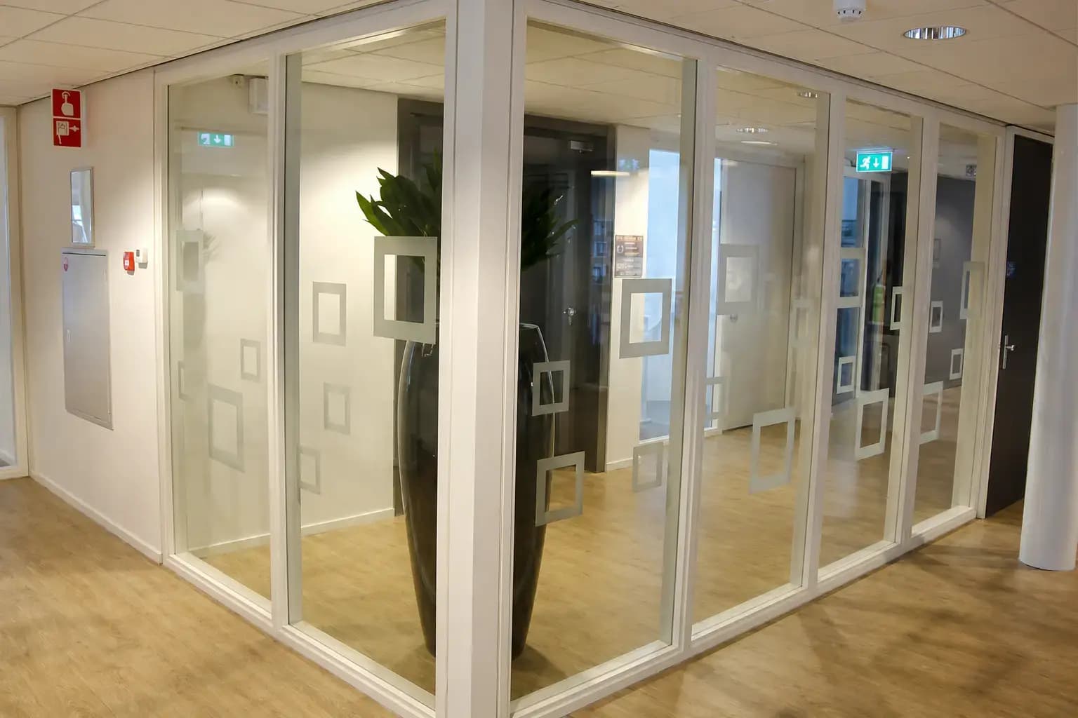 Glazen kantoorwanden met matte vierkante raamfolie als decoratieve privacyfolie in een moderne gang.