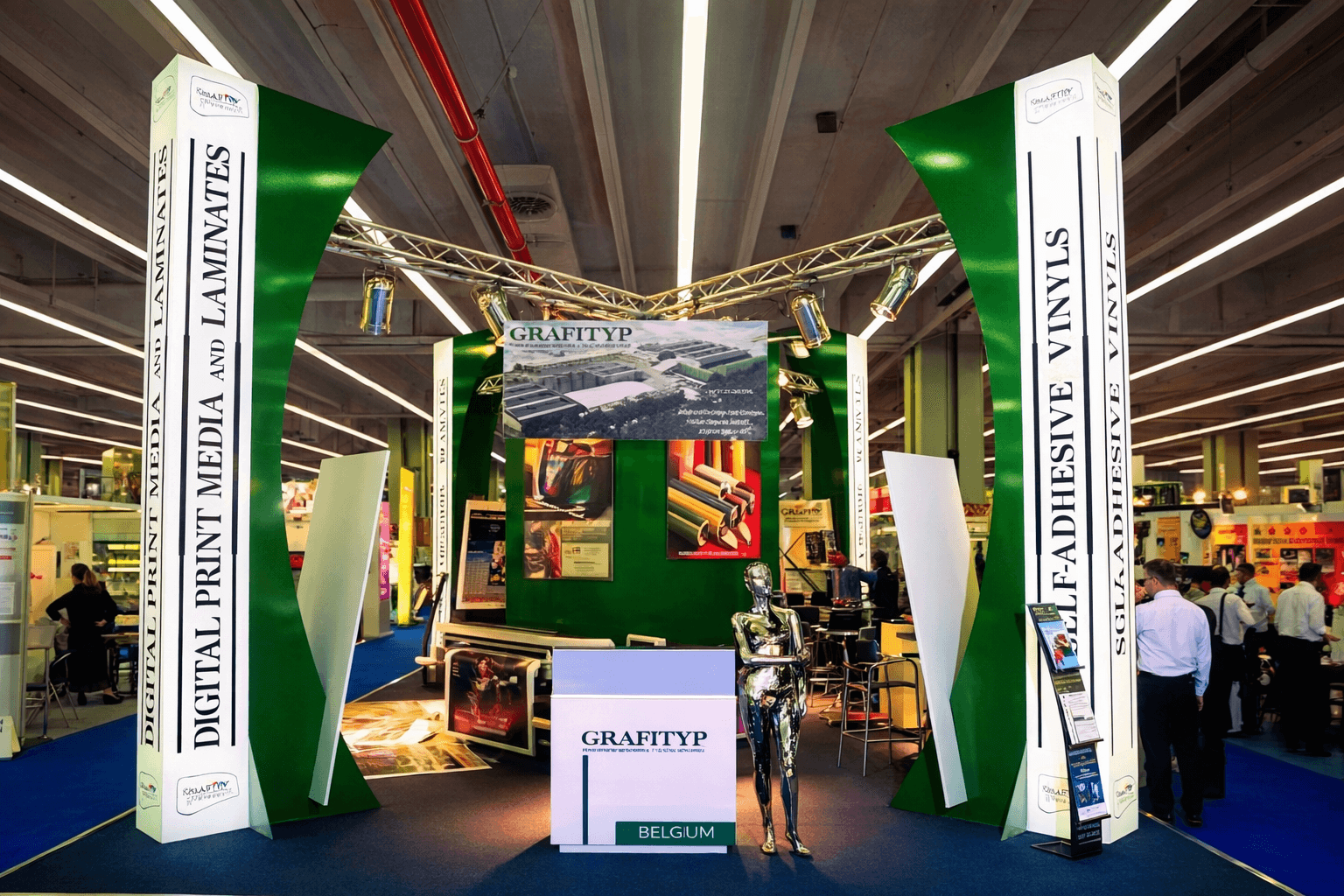 Groen-witte beursstand van GRAFITYP met hoge signzuilen, balie, groot displayscherm en productpresentatie voor printmedia, laminaten en zelfklevende vinyls op een vakbeurs.