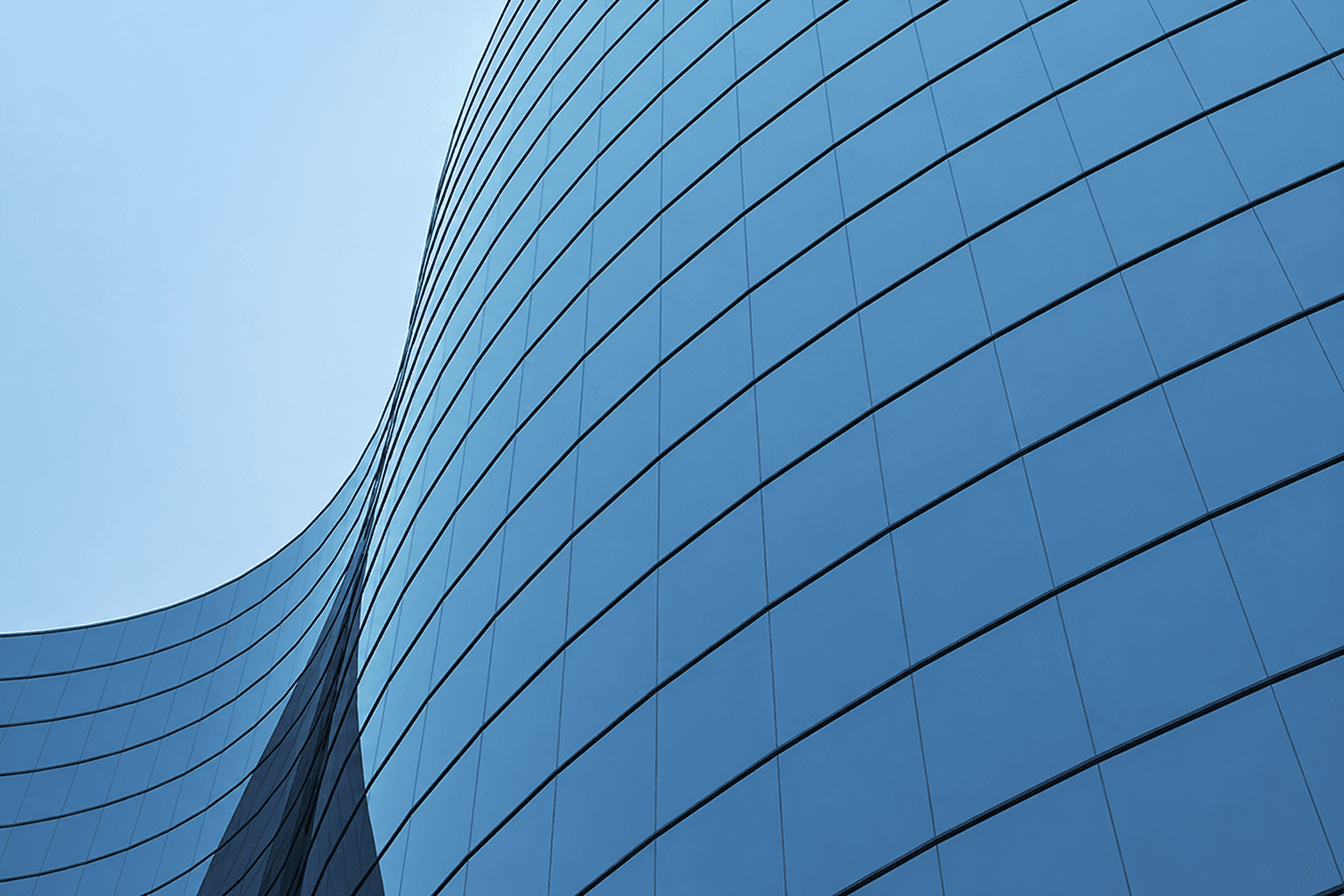 Reflecterende blauwe glasgevel met grote raampanelen op een modern kantoorgebouw.