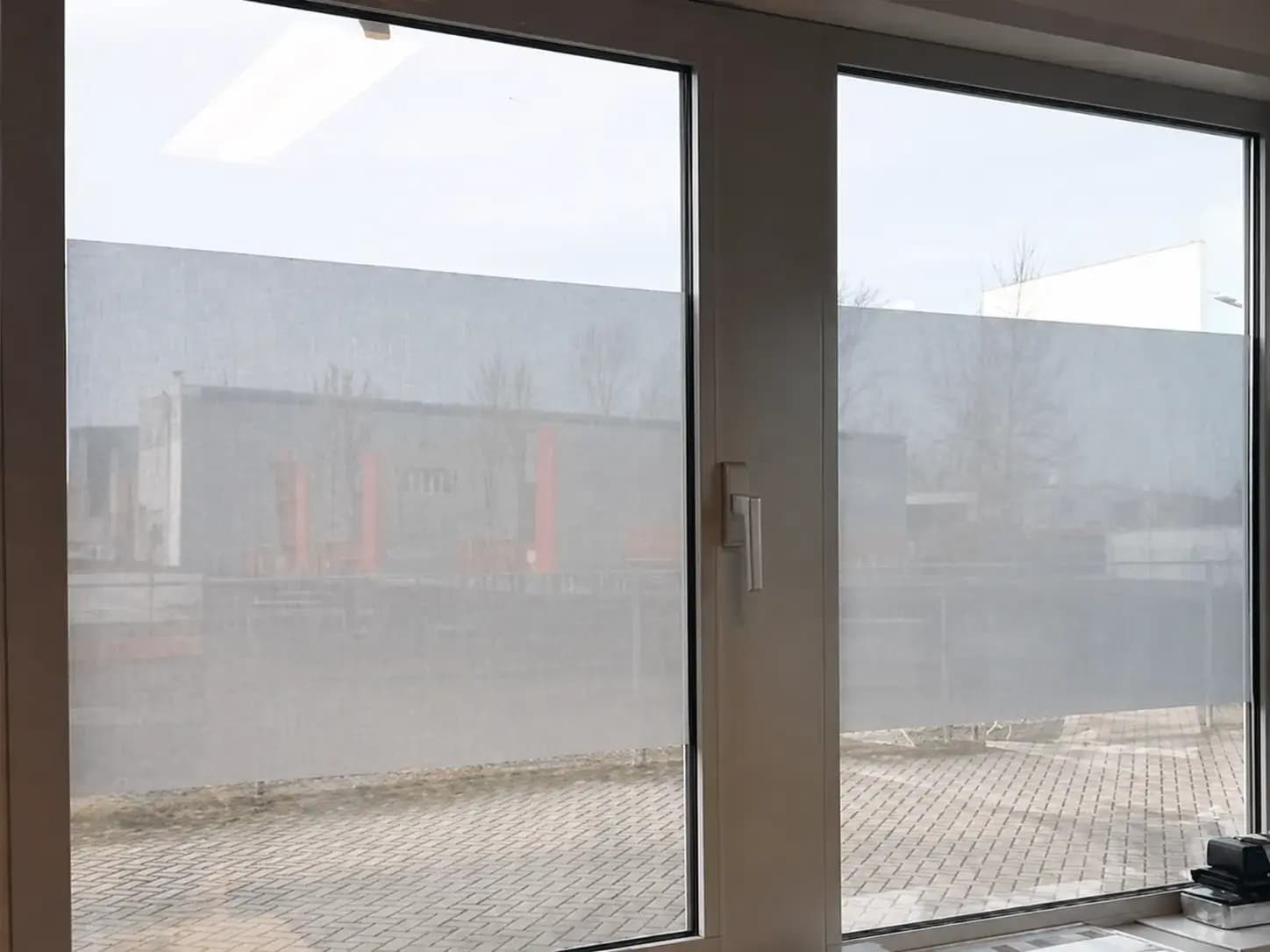 Matte raamfolie op grote kantoorramen met aluminium kozijnen, toegepast als horizontale privacyfolie met behoud van lichtinval.