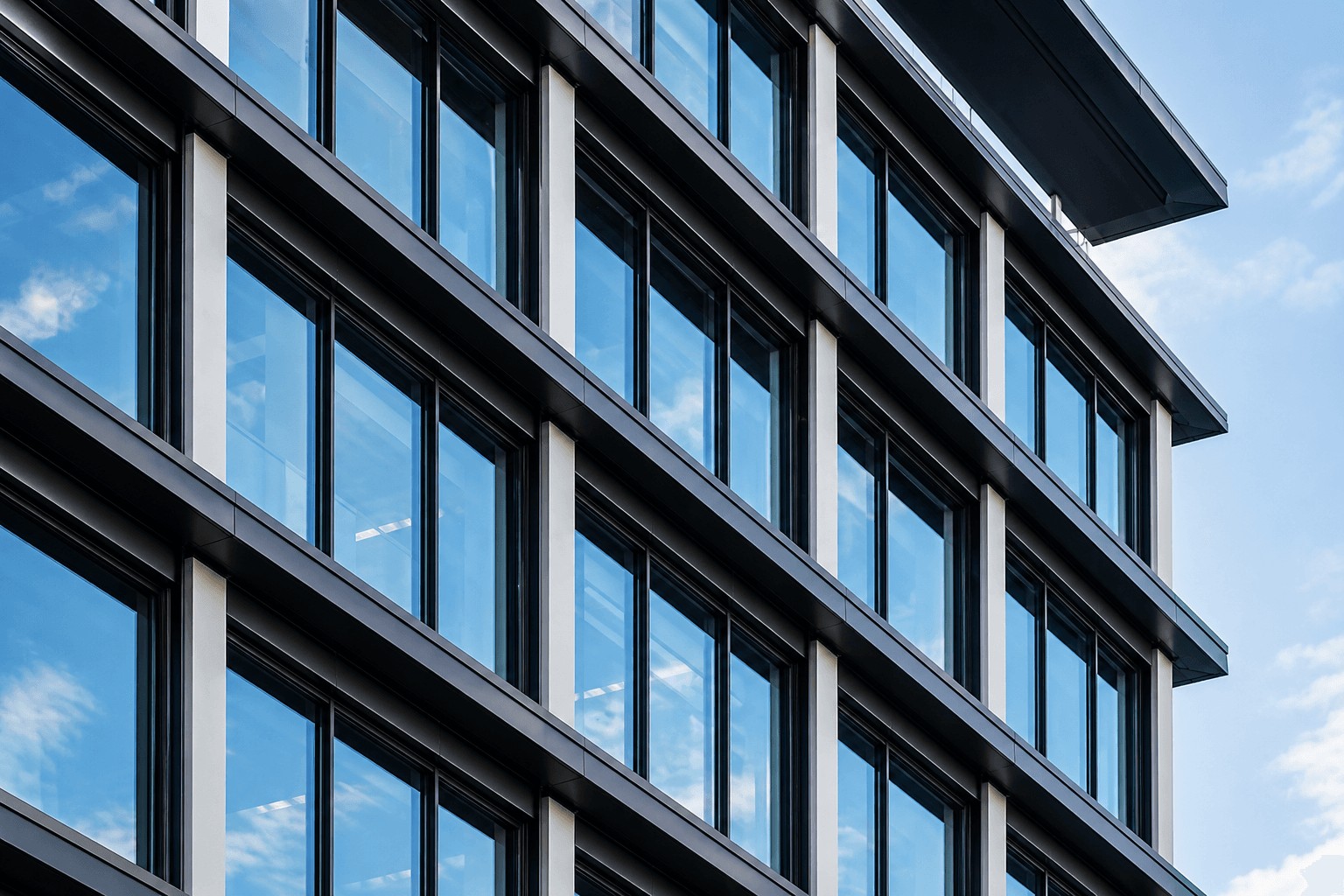 Moderne kantoorgevel met blauwe reflecterende raampanelen en strakke zwarte kozijnen.