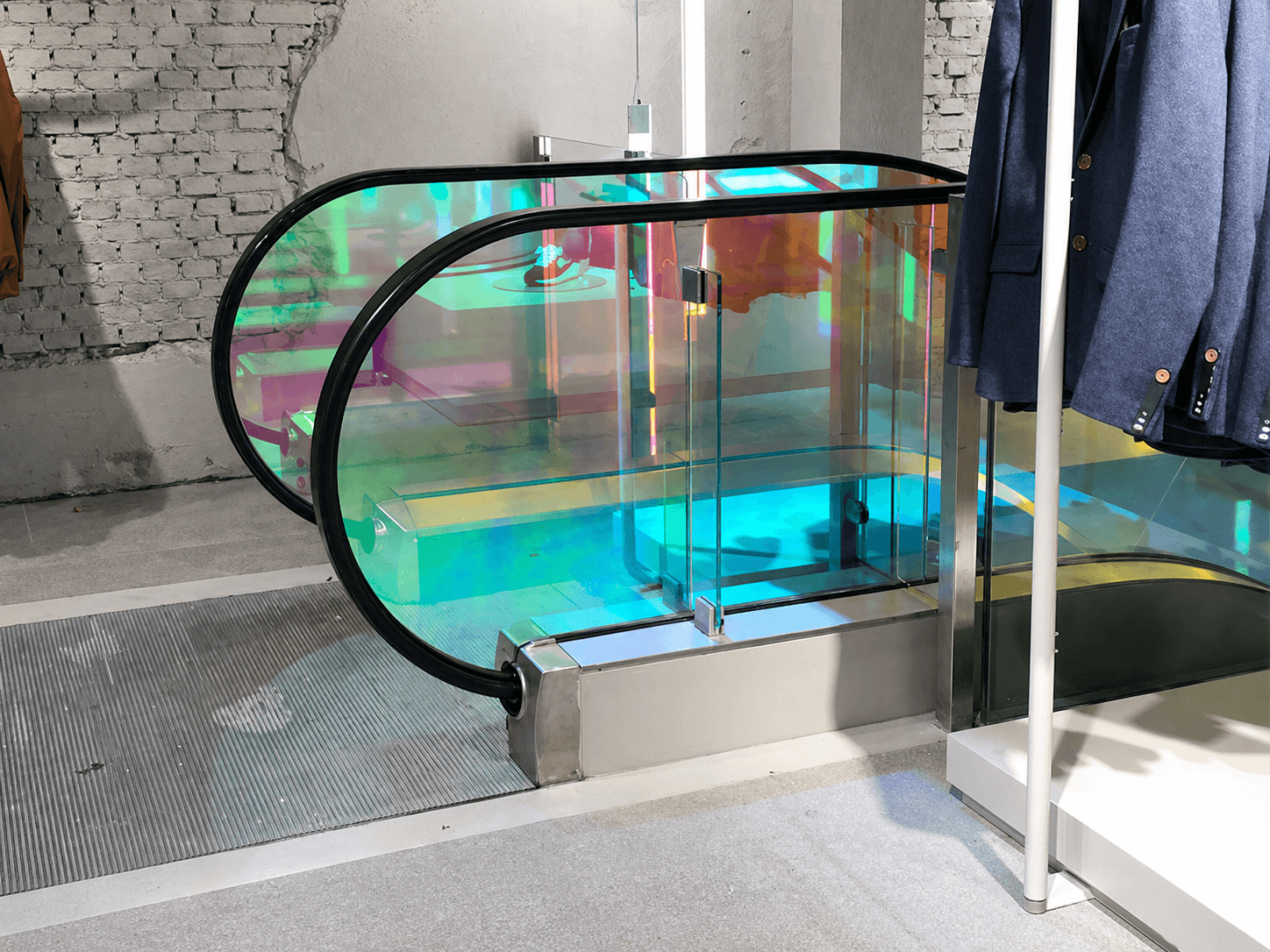 Roltrap in winkelinterieur met transparante iriserende glasfolie op de balustrade, toegepast als kleurrijke decoratieve folie en interieurvisual.