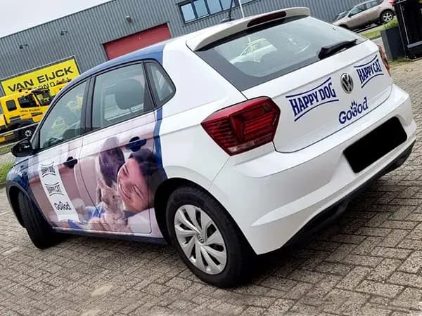 Witte personenauto met full-colour voertuigbelettering voor diervoeding, voorzien van fotoprint op de zijpanelen en merklogo’s op de achterklep op een bedrijventerrein.