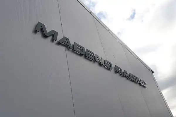 Witte gevel van een bedrijfspand met donkere 3D gevelletters "MADERO RACING" hoog gemonteerd als strakke gevelreclame.