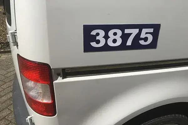 Een witte bestelwagen met een blauwe magneetplaat waarop het nummer 3875 staat.
