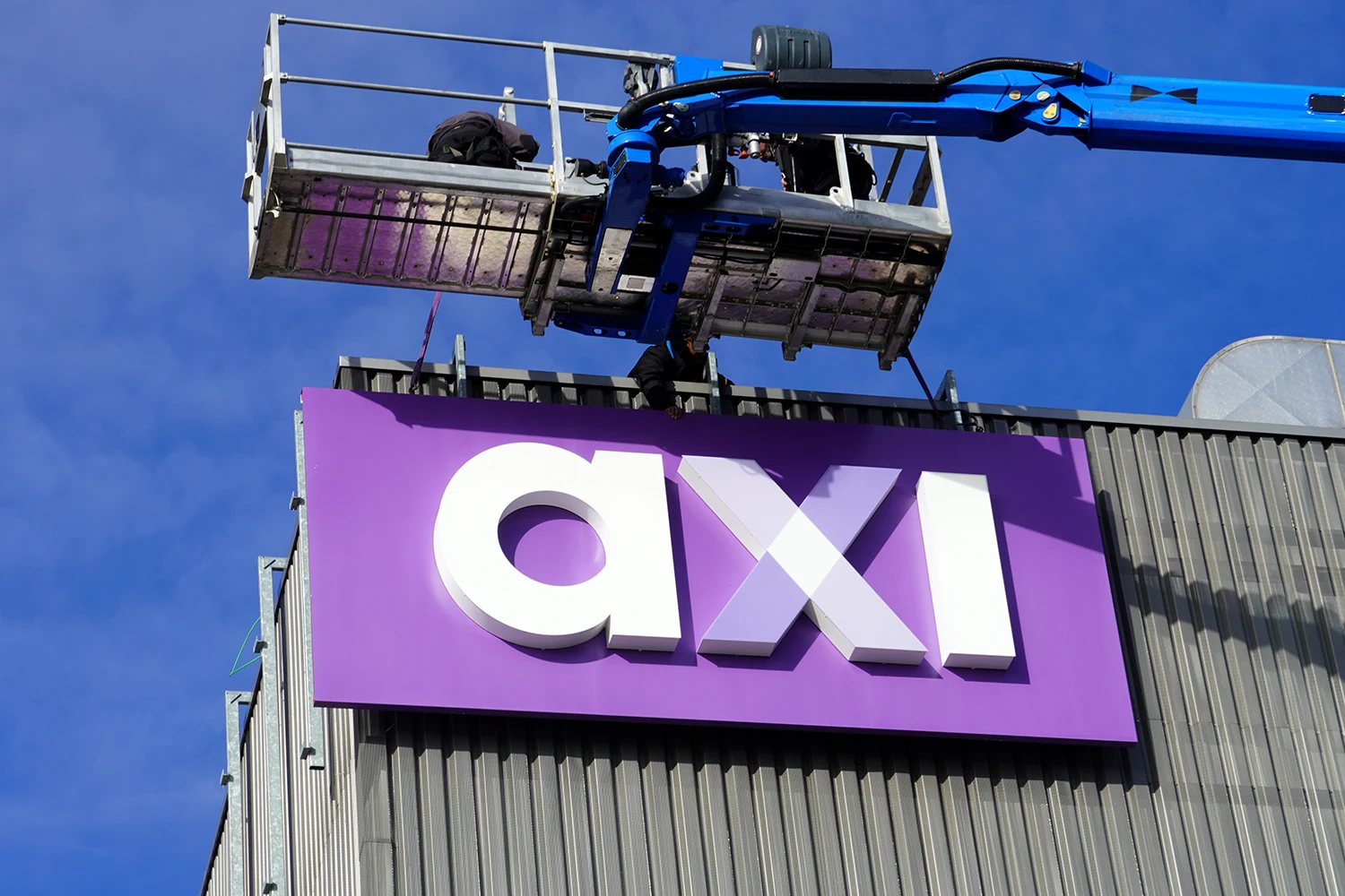 Montage van AXI-gevelreclame met een blauwe hoogwerker