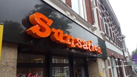 boxletters sunsation oranje op een wand in een winkelstraat
