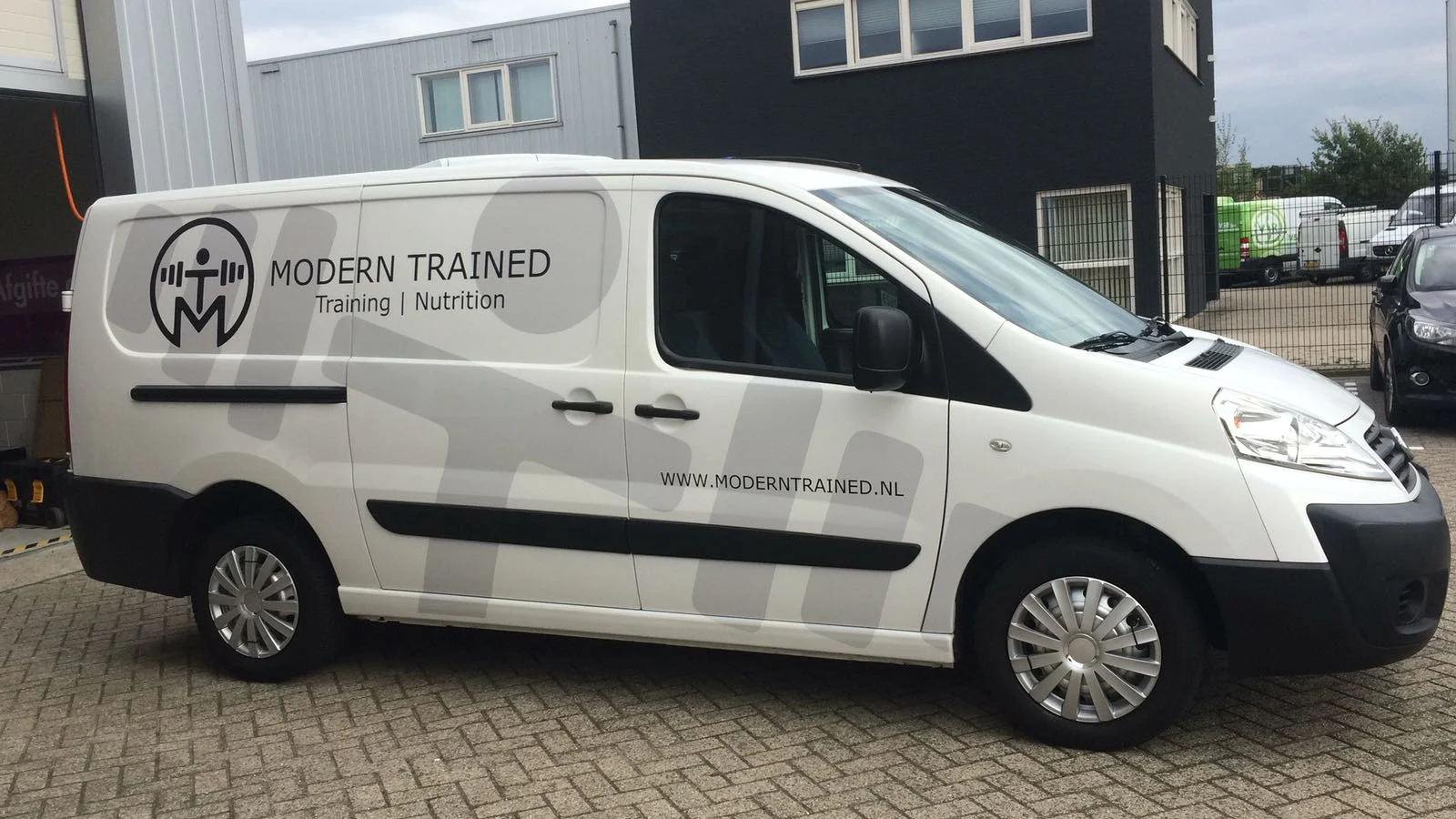 White van with a Modern Trained logo and grey pattern.