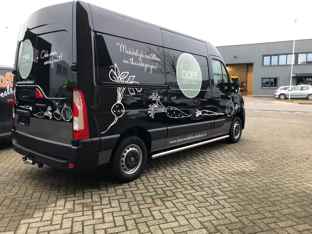 Black Boer farm shop van with white vegetable illustrations.