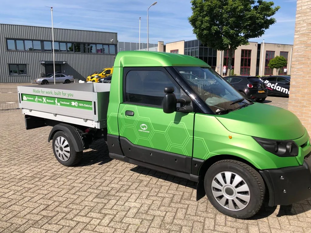 Green electric Streetscooter with white vehicle graphics.