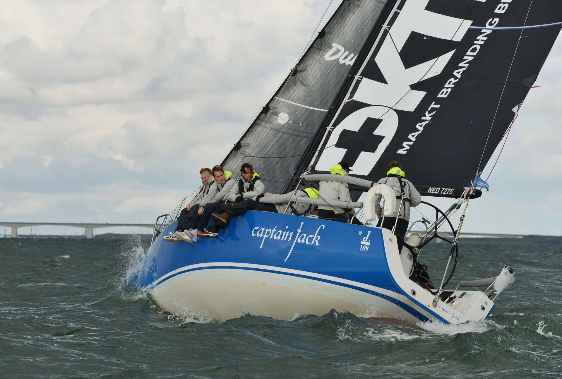Captain Jack sailing boat with a blue hull and white boat name under sail.