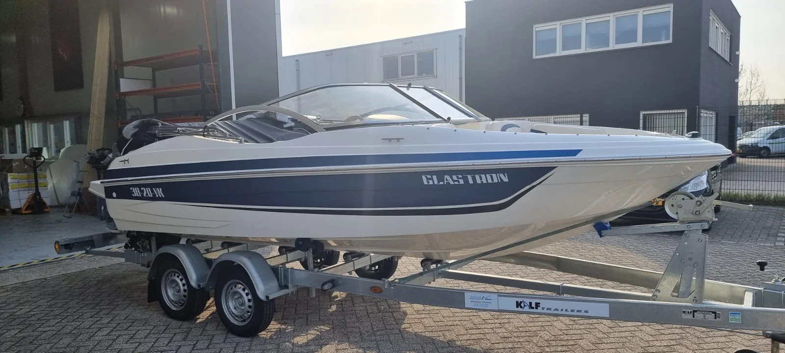 Glastron speedboat with blue and grey stripes on a trailer.