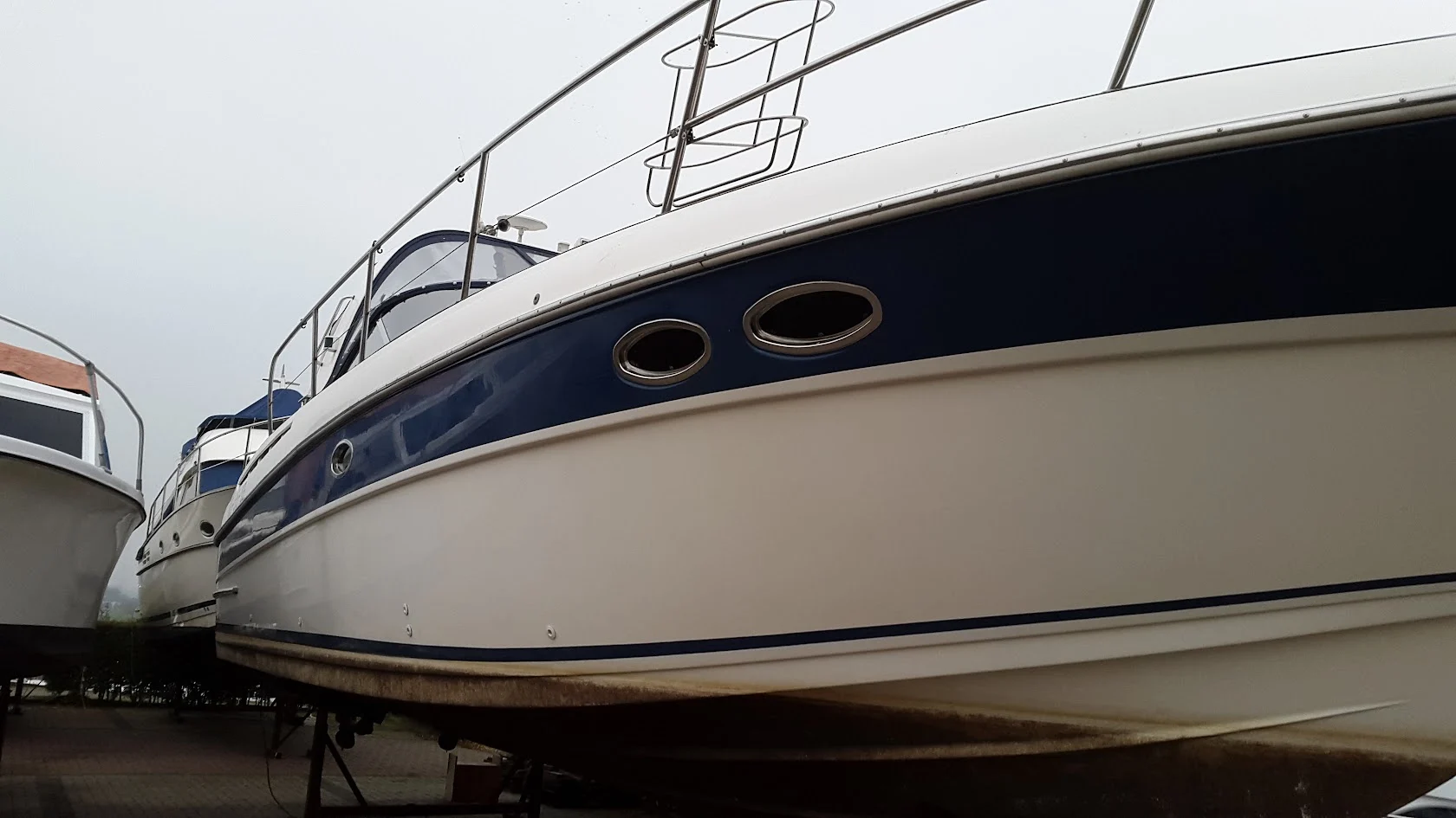 Detail of blue hull stripes and portholes on a motorboat.