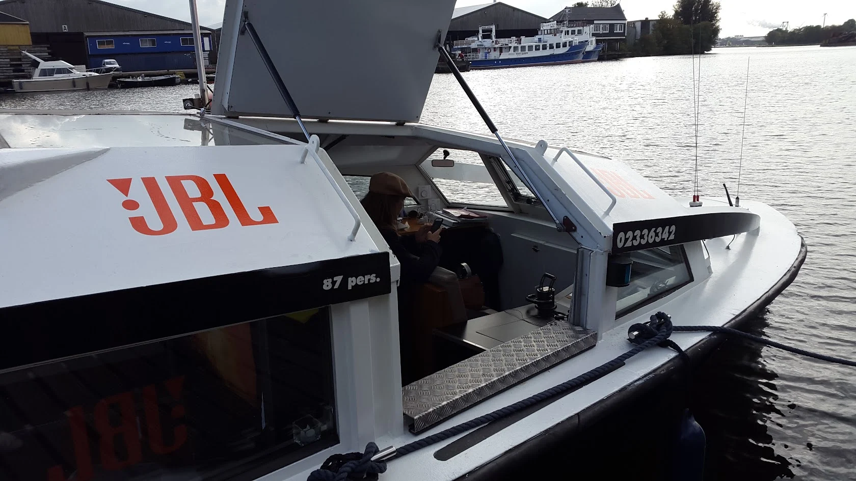 White passenger boat on the water with orange JBL lettering.