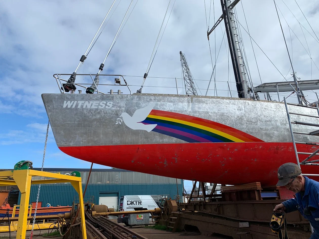 Witness sailing boat with white dove and rainbow hull graphics.