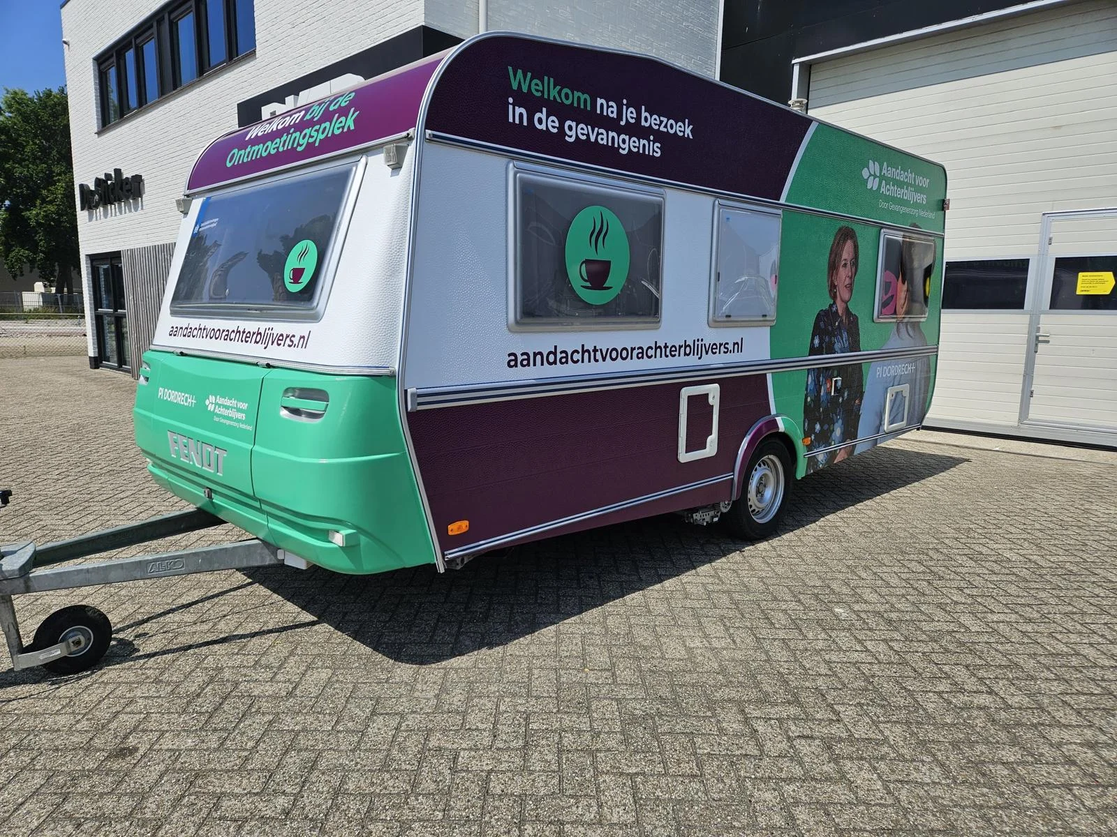 Front and side of the green and purple Aandacht voor Achterblijvers caravan.