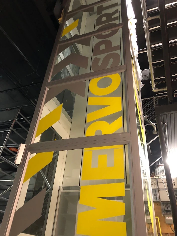 Tall glass partition with yellow and grey Mervo Sport lettering