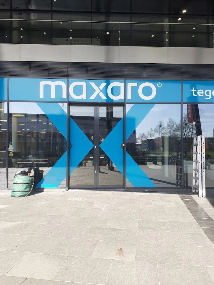 Shop entrance with a turquoise Maxaro logo and large colour panels on glass