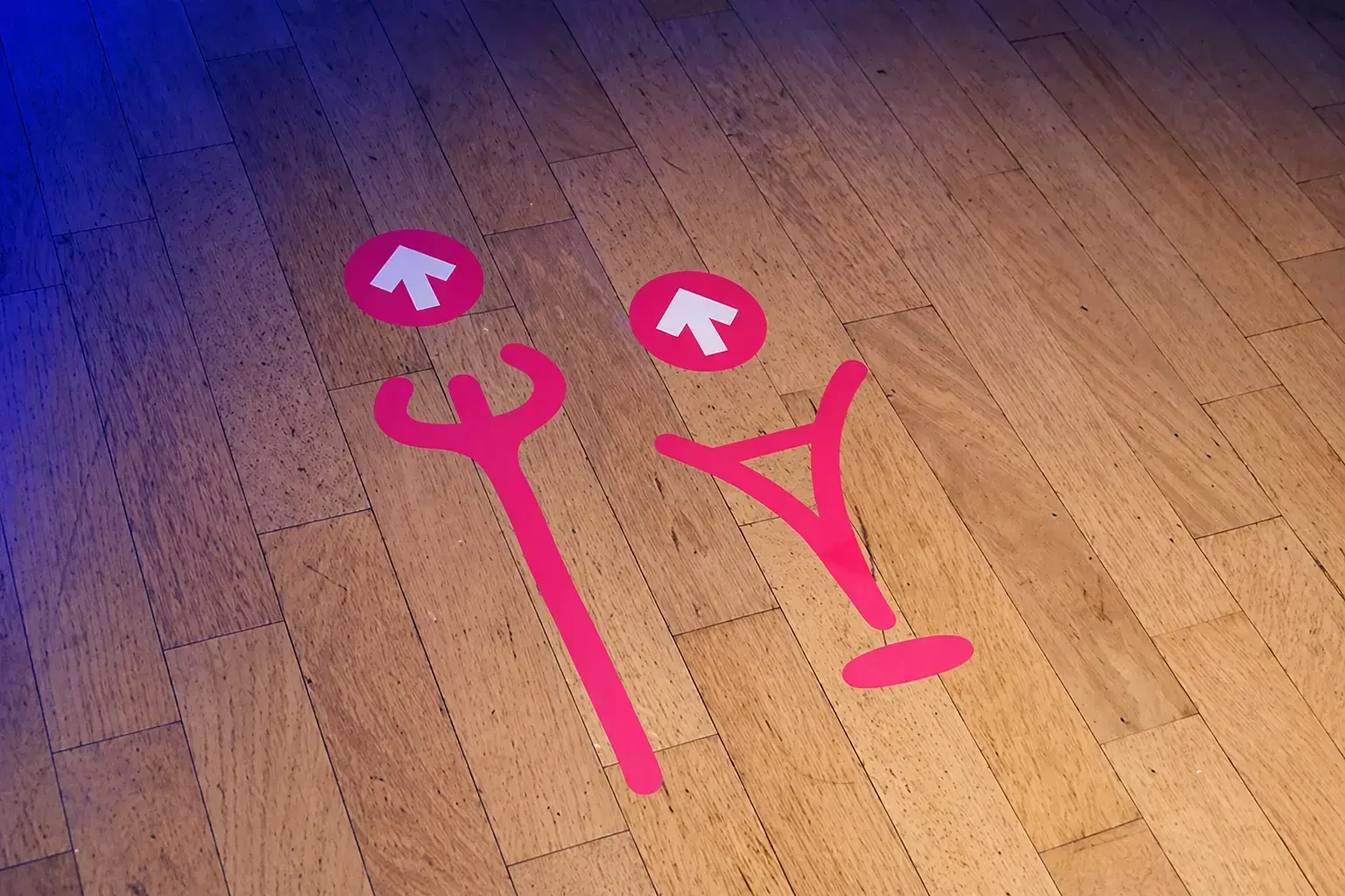 Pink directional arrows and symbols on a wooden floor