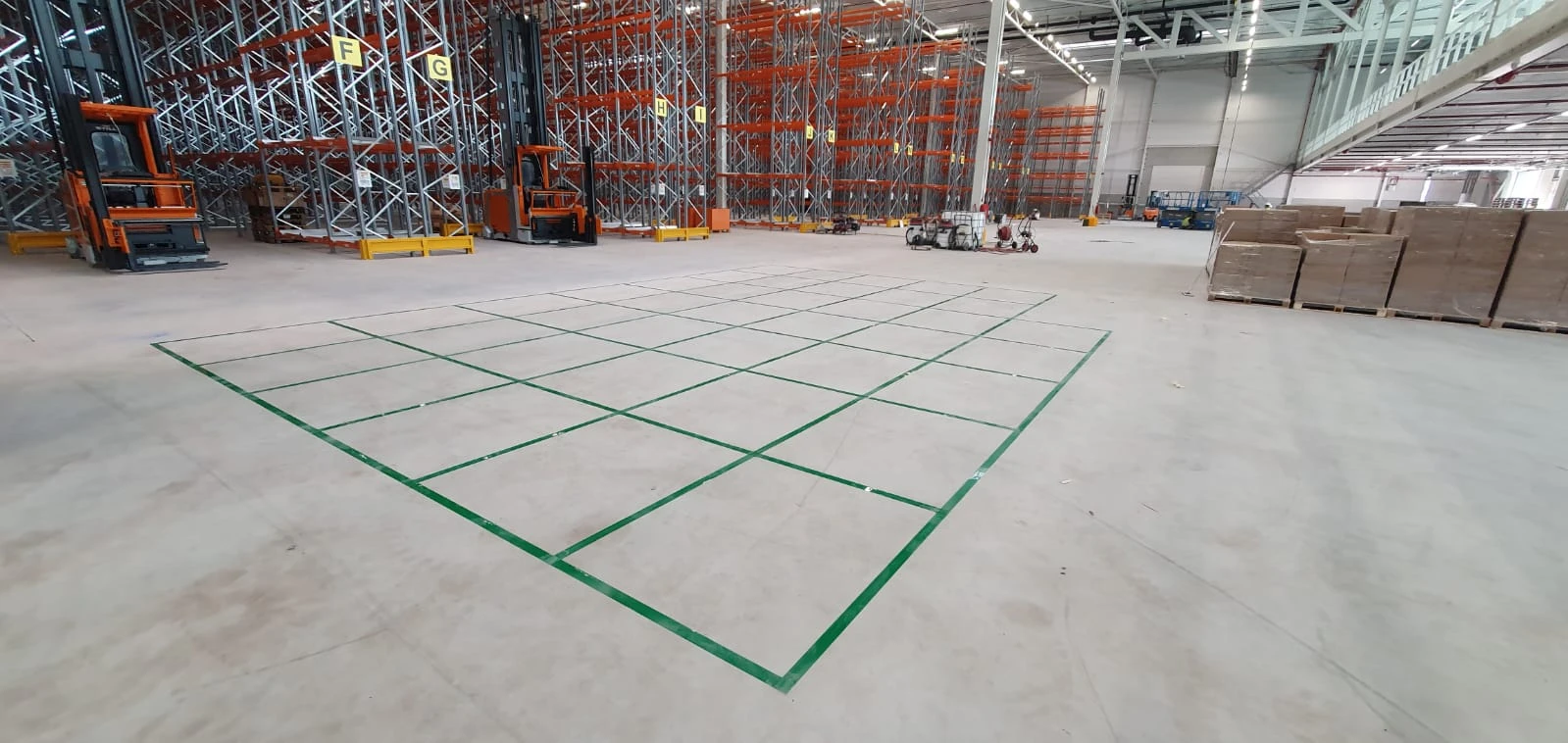 A green grid of designated storage bays on a warehouse floor