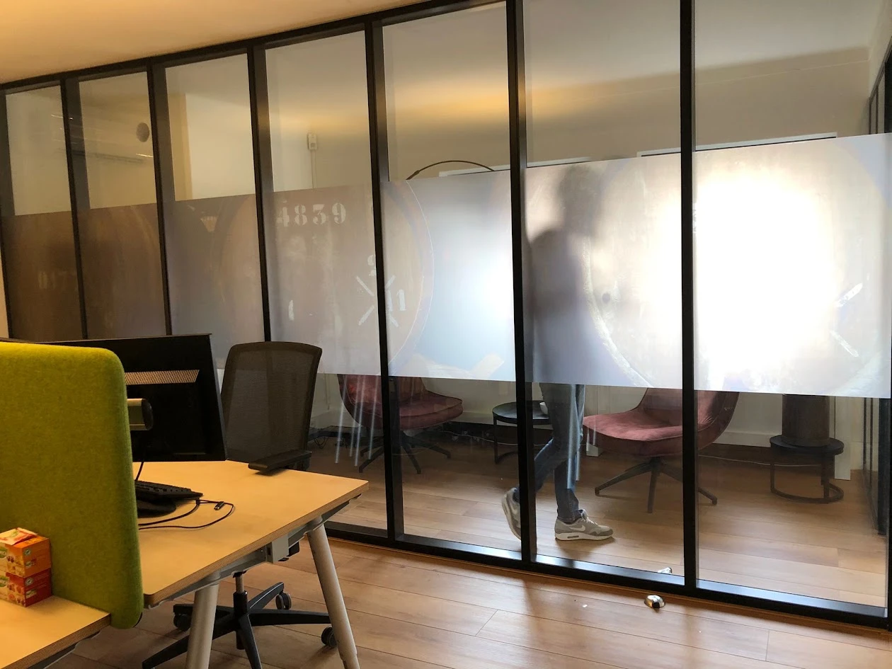 Frosted band with a cut-out design on a glass office partition, with clear glass above and below