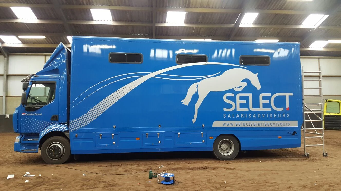 Blue horsebox with a white jumping horse and Select sponsor graphics