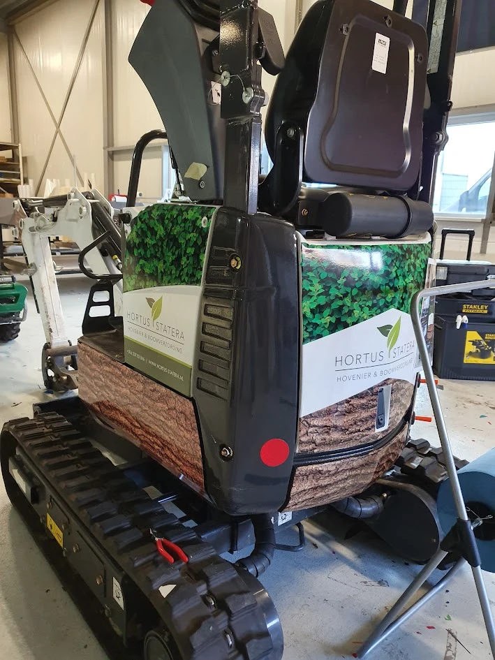Compact excavator with Hortus Statera lettering and leaf and tree bark graphics