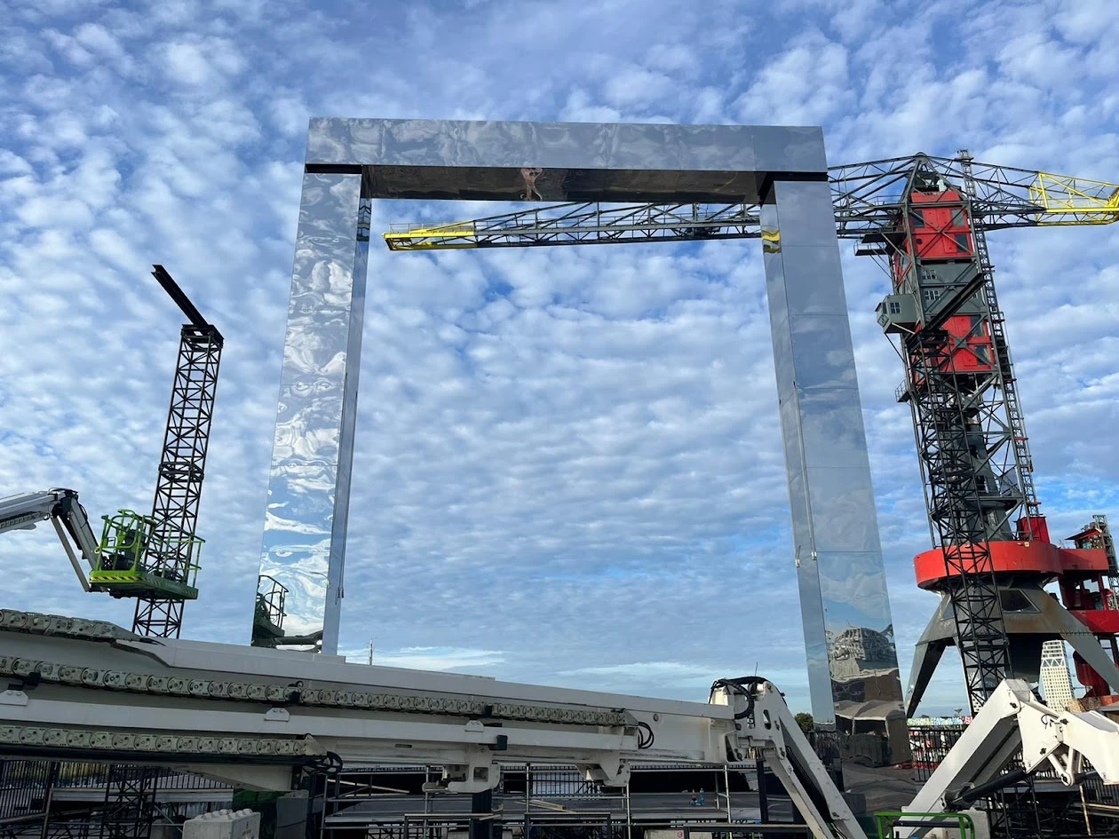 Montage van een groot zilverkleurig spiegelend frame met hoogwerkers