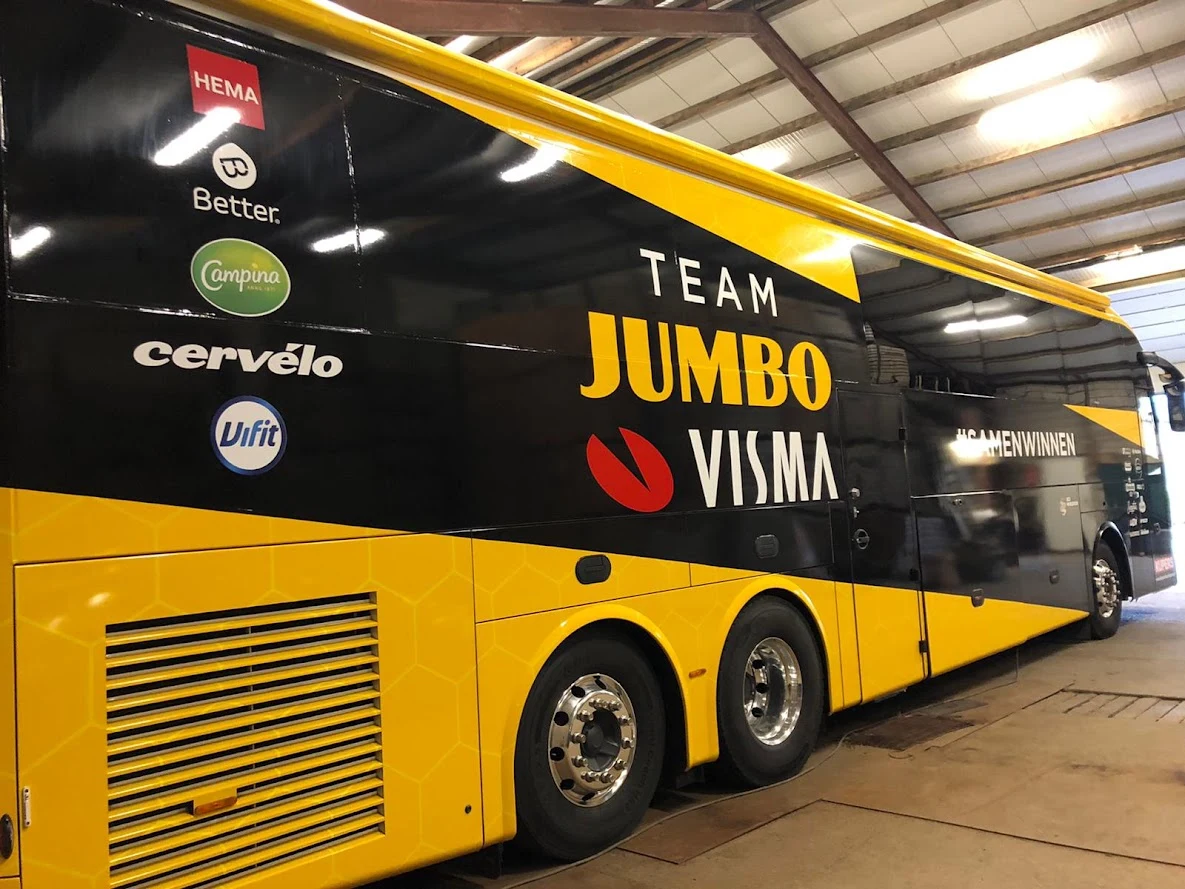 Side of a Team Jumbo-Visma coach with a yellow and black wrap and sponsor logos