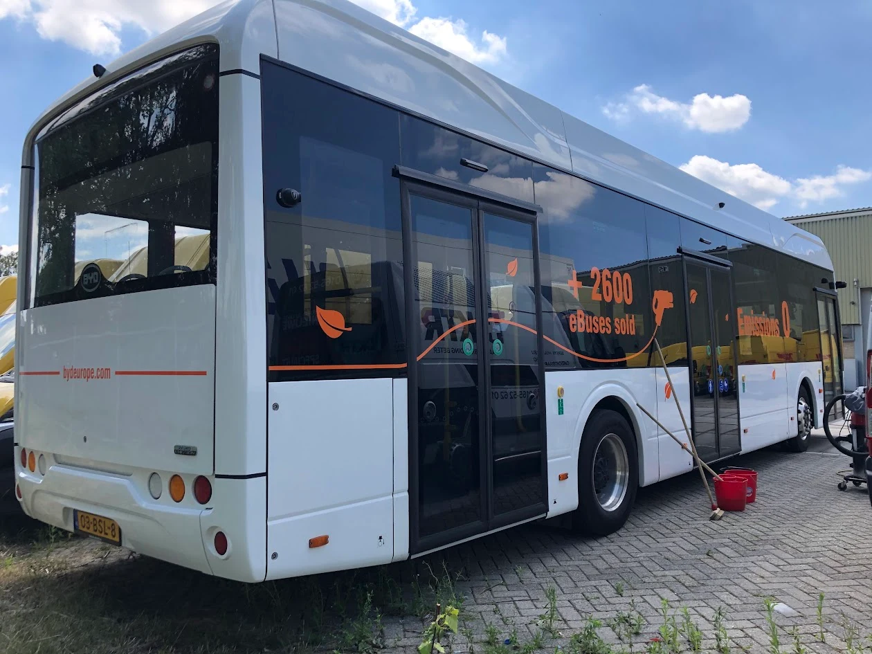 BYD bus with orange campaign lettering and decorative lines