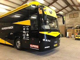Front of a yellow and black team coach in the workshop
