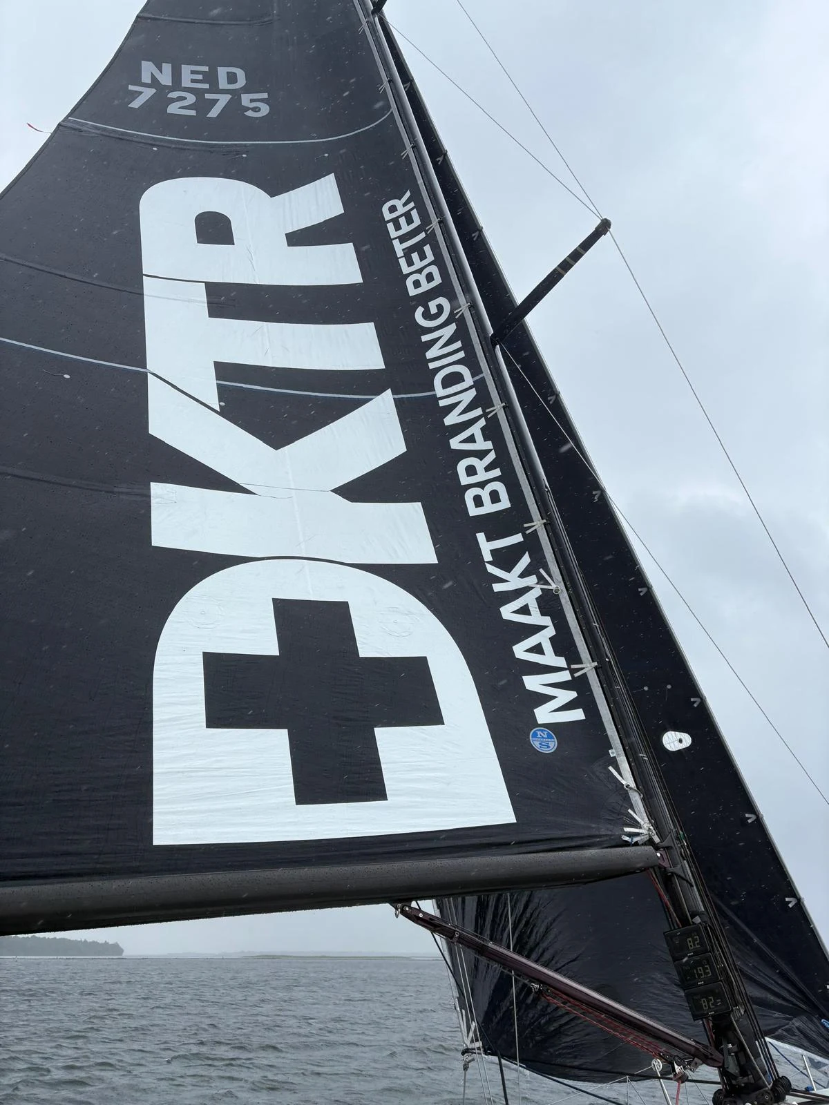 Detail of white DKTR sponsor graphics on a dark racing sail