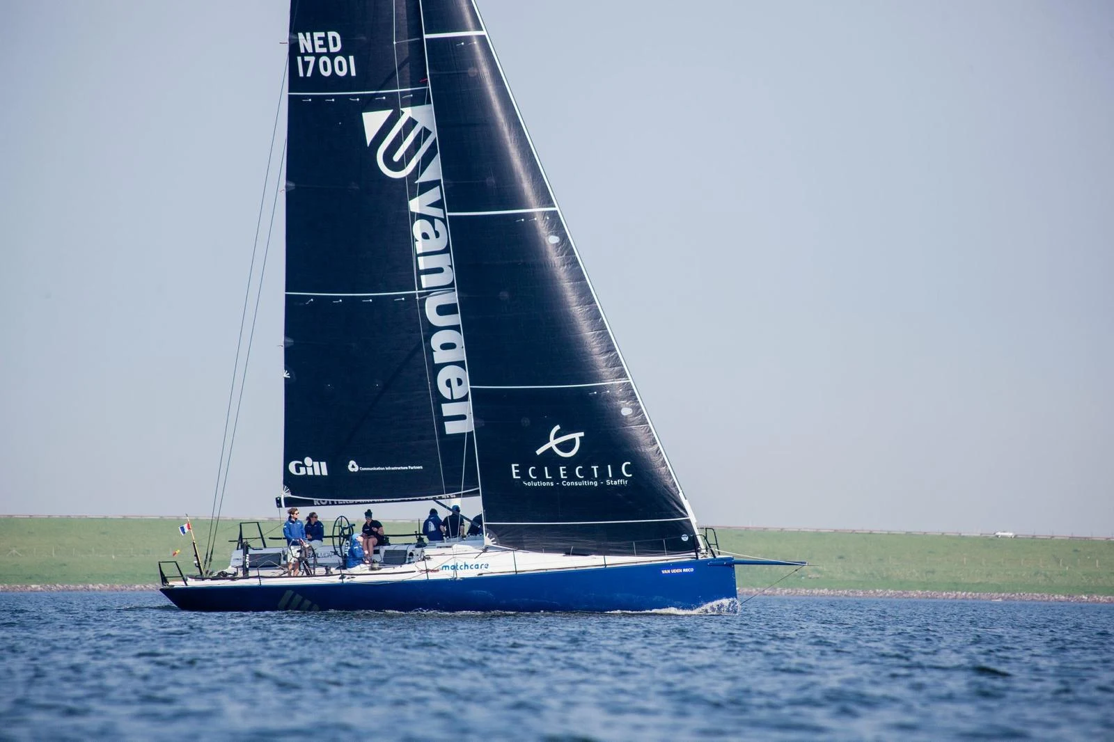 Sailing yacht with Van Uden and Eclectic sponsor logos on dark sails